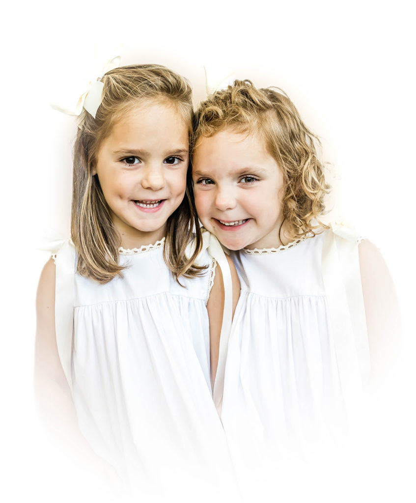 Color Heirloom Portrait Twin Girls Wearing white sleeveless dresses Smiling at the Camera 