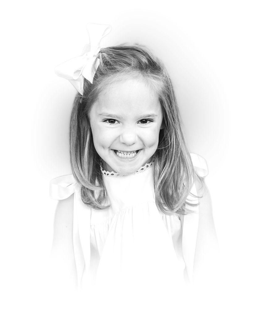 Timeless black and white portrait little girl in white dress smiling at camera
