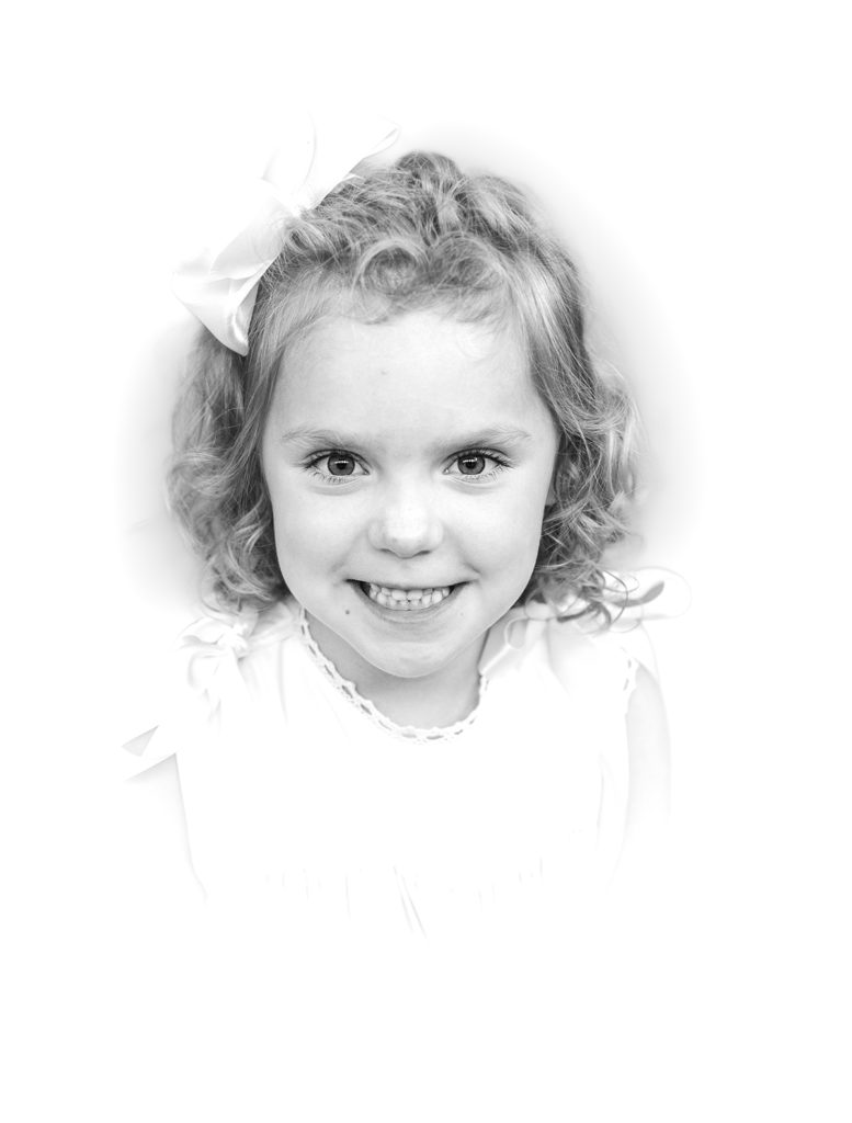Black and White Heirloom Portrait little girl wearing a white dress with ecru ribbons smiling at the camera