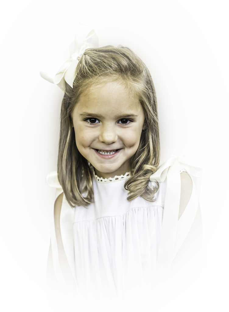 Color Heirloom Portrait little girl wearing a white dress with ecru ribbon smiling at the camera
