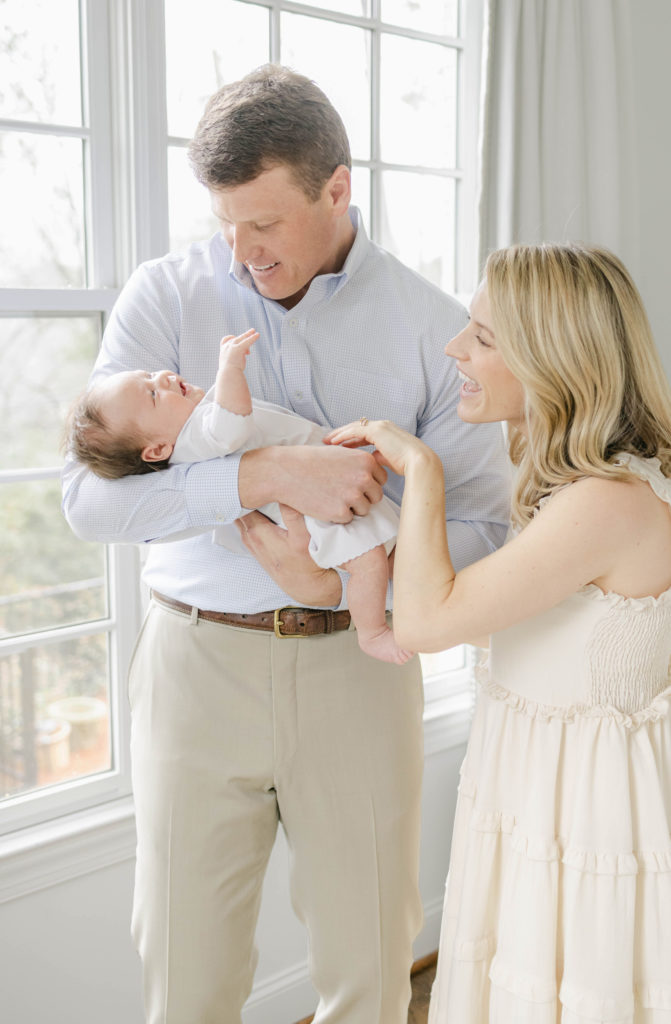 Family of 3 in front of a bright window at lifestyle newborn session by Mountain Brook newborn photographer 