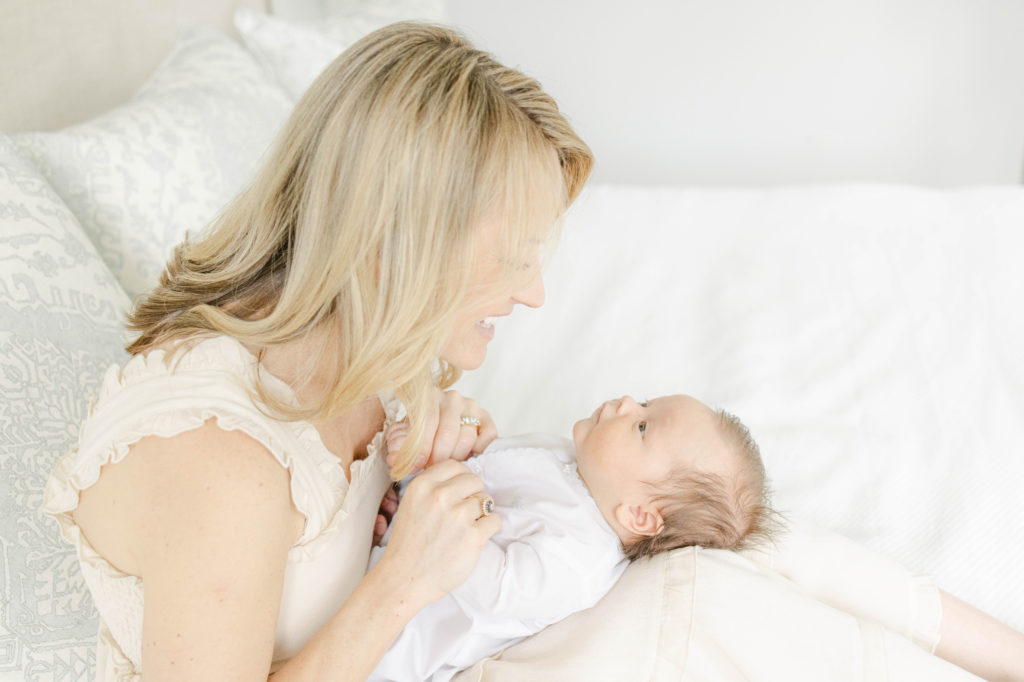 Mom sitting on the bed and talking to newborn baby boy by Mountain Brook newborn photographer 