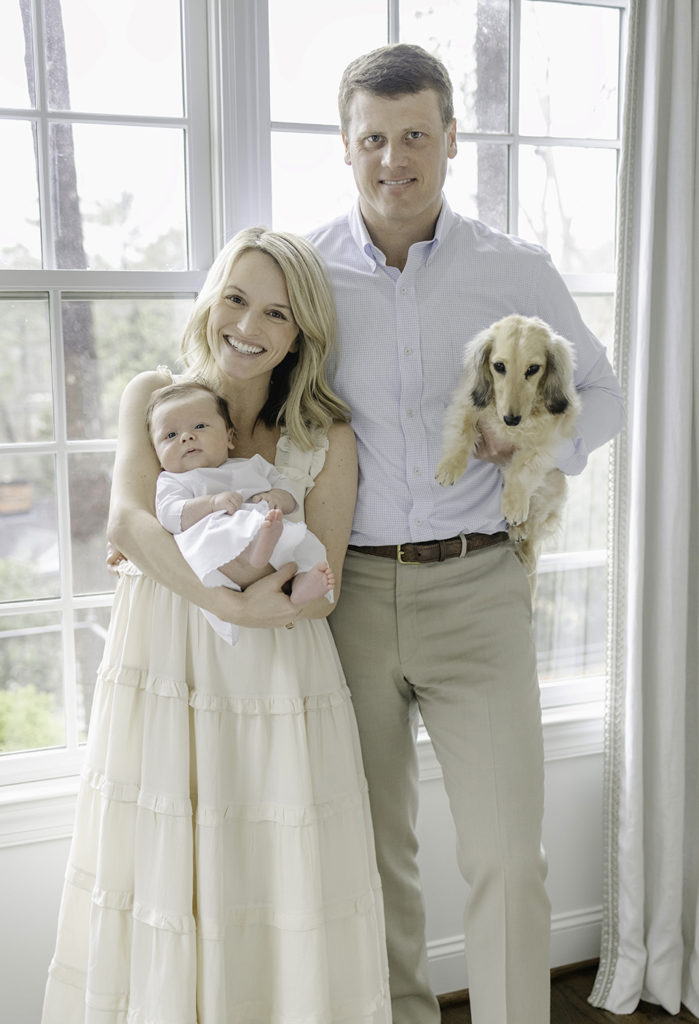 Family of 3 standing in front of a window with dog at a newborn session by Mountain Brook newborn photographer 