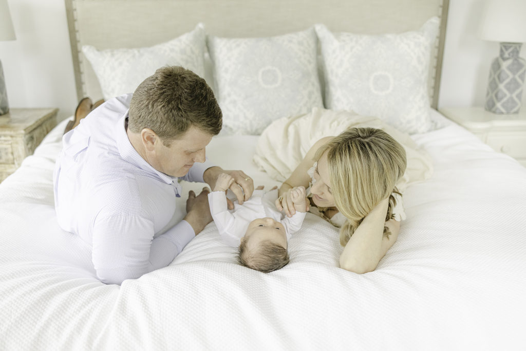 Mom, Dad, and Baby lying on the bed together by Mountain Brook newborn photographer 