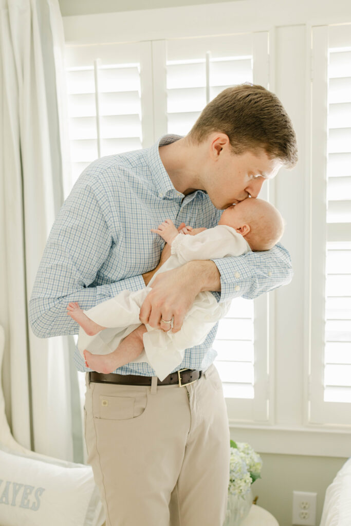 Dad holding and kissing newborn by Birmingham Newborn Photographer