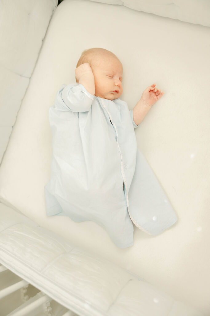 Newborn baby in blue daygown lying in crib by Birmingham Newborn Photographer