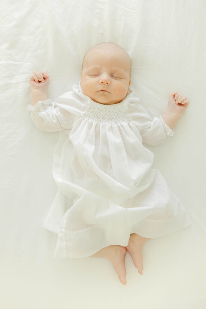 Sleeping newborn baby boy in white daygown by Birmingham Newborn Photographer