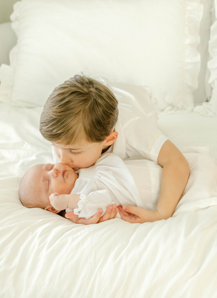 Older brother kissing newborn baby brother by Birmingham Newborn Photographer