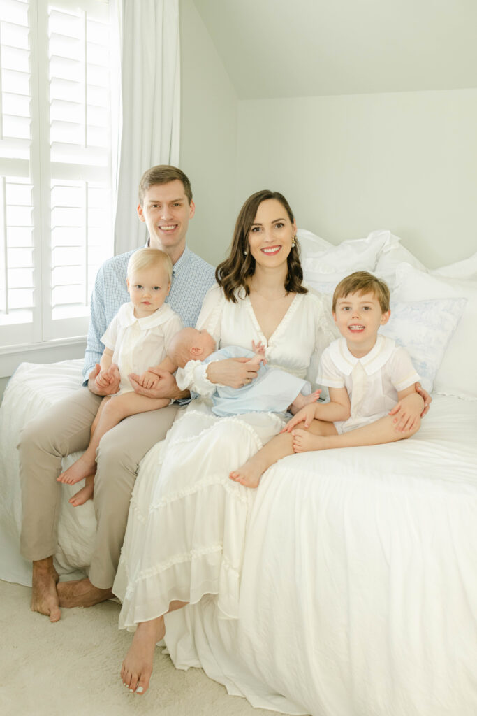 Family of 5 sitting on the bed at a newborn session by Birmingham Newborn Photographer