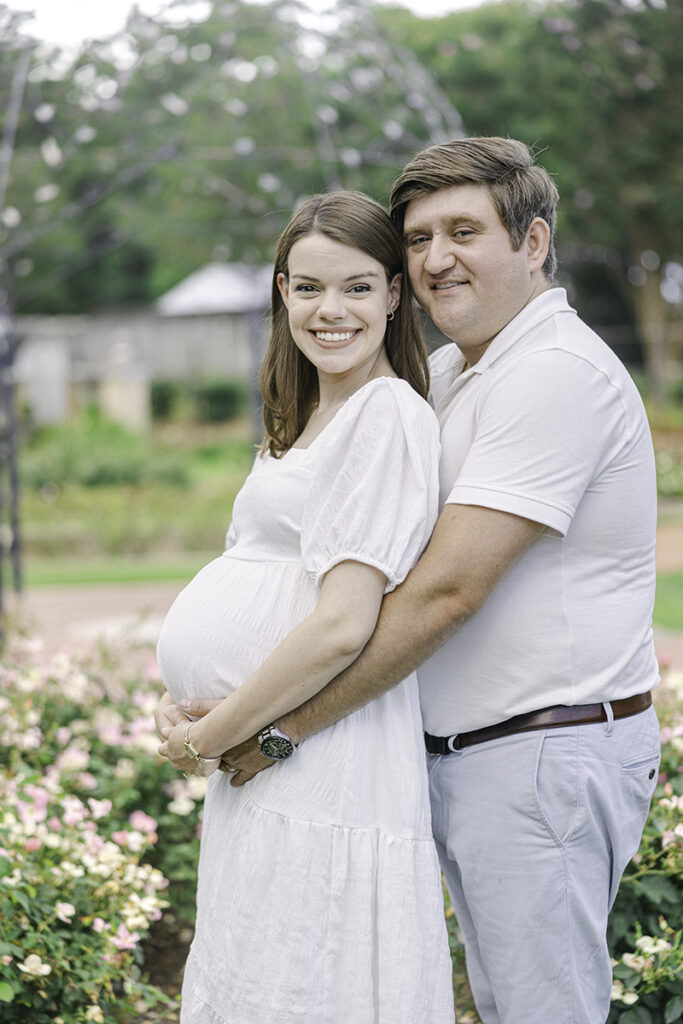 Pregnant Mom and dad holding onto pregnant belly smiling at camera by Birmingham Maternity Photographer 