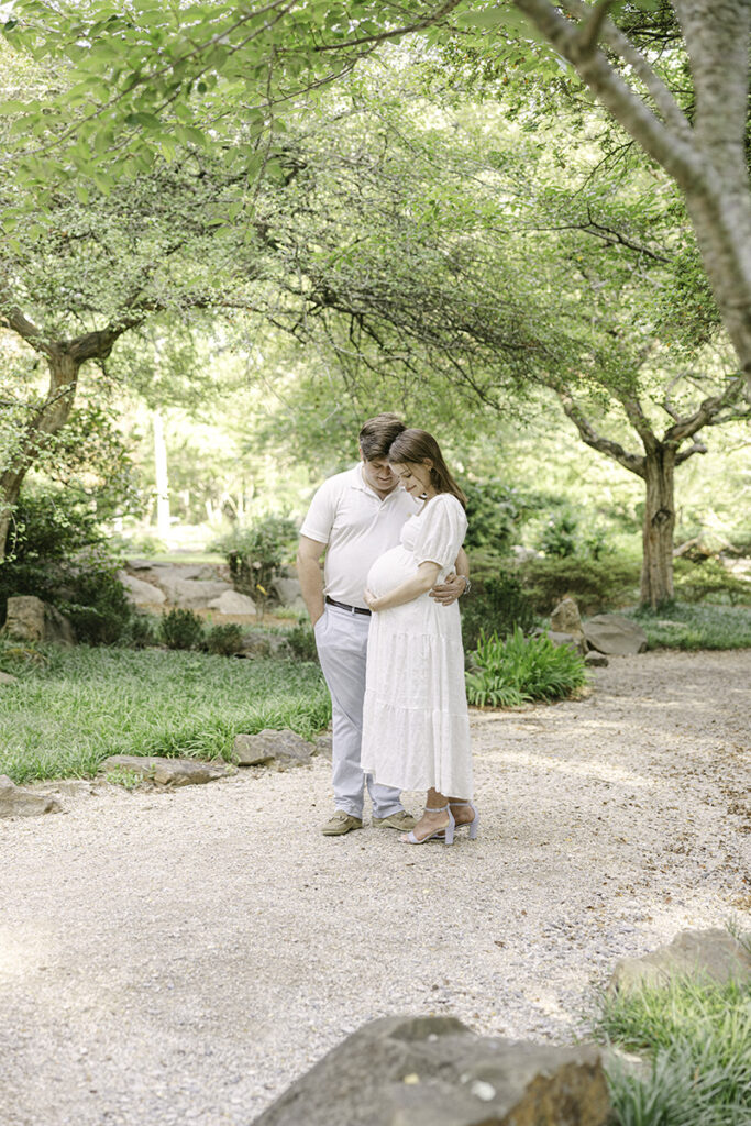 Mom and Dad hugging and smiling down at Baby Bump by Birmingham Maternity Photographer