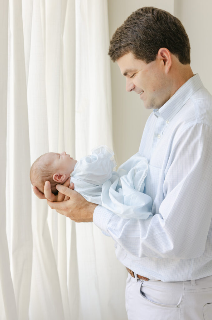 Dad smiling down at baby boy in newborn lifestyle photoshoot