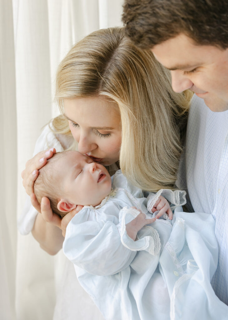 Mom and dad looking down on newborn in lifestyle studio session